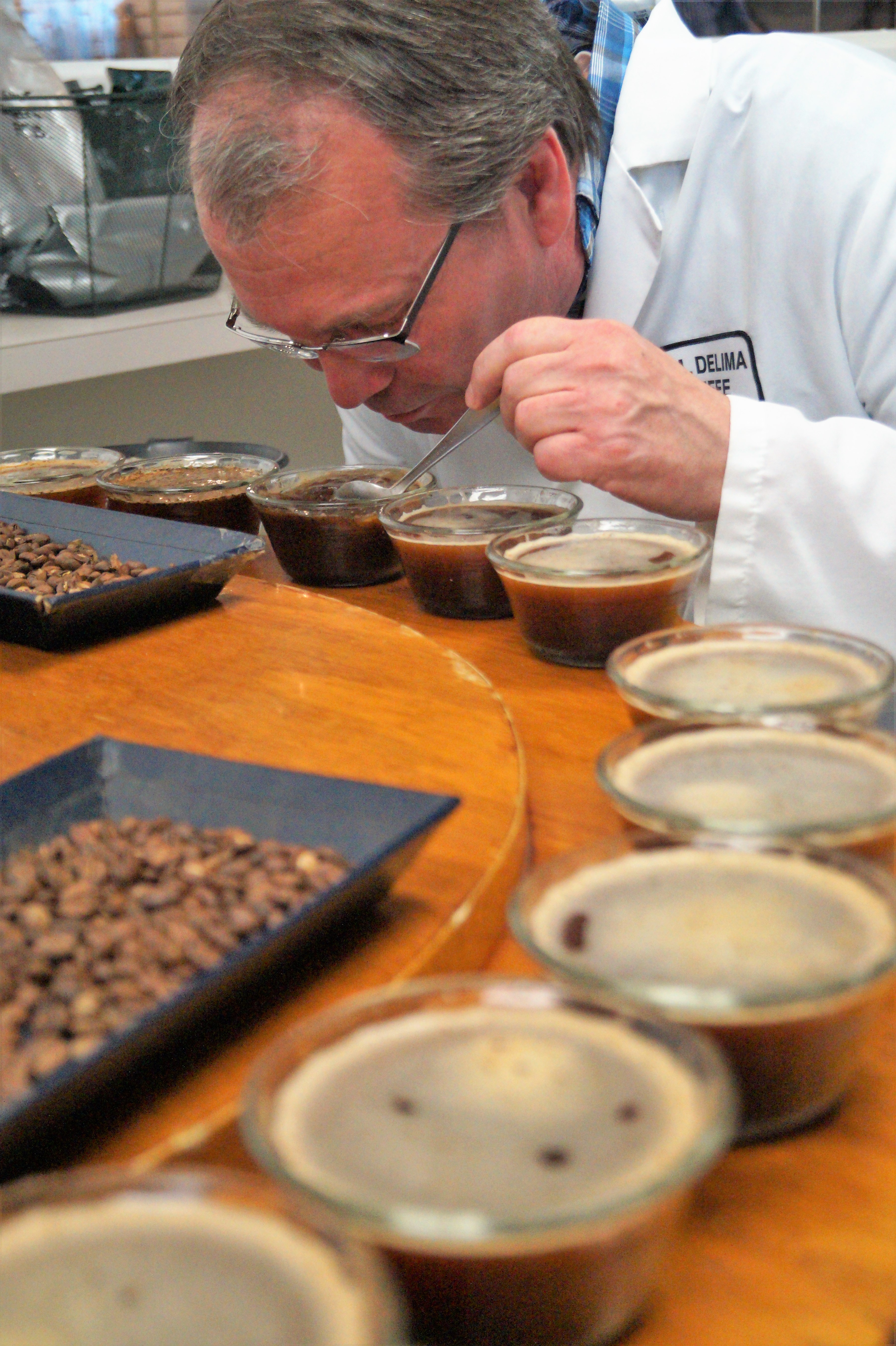 Glenn breaks the crust that forms on the top of the coffee during the cupping process as the coffee grinds soak.