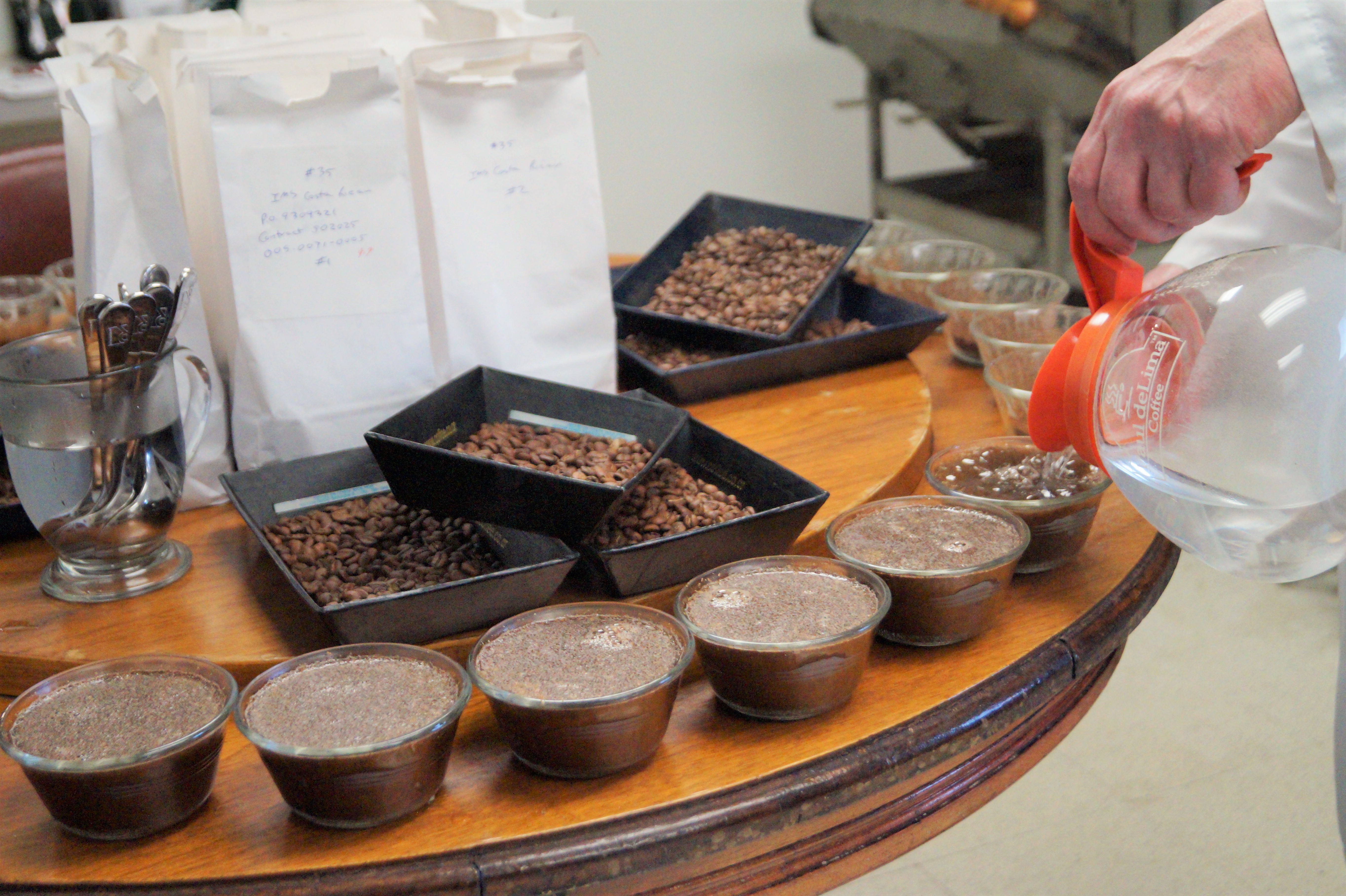 Glenn pours hot water over the coffee grounds to steep them prior to tasting during the cupping process.
