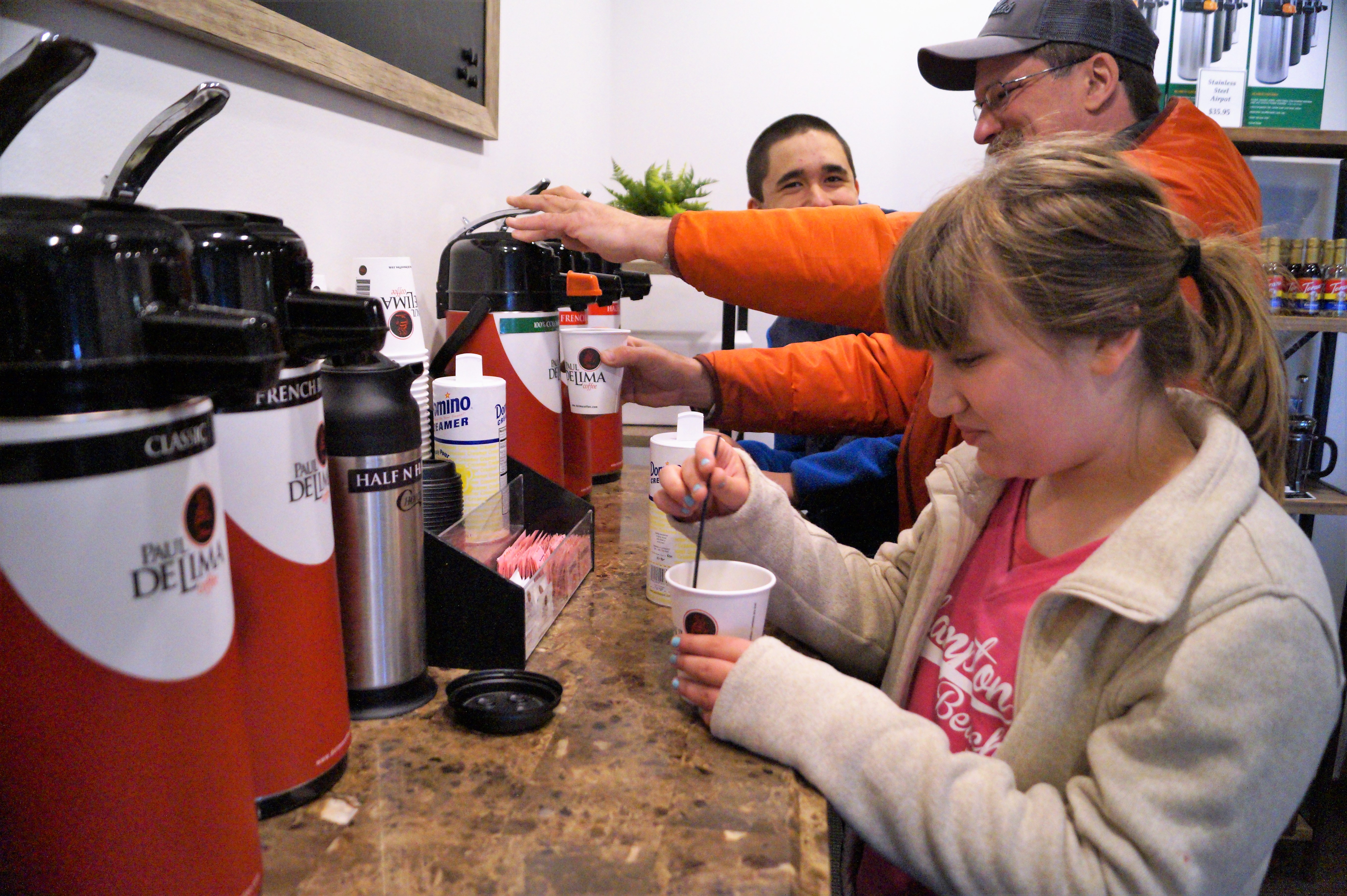Customers getting coffee at the complementary coffee bar at the Paul deLima store.