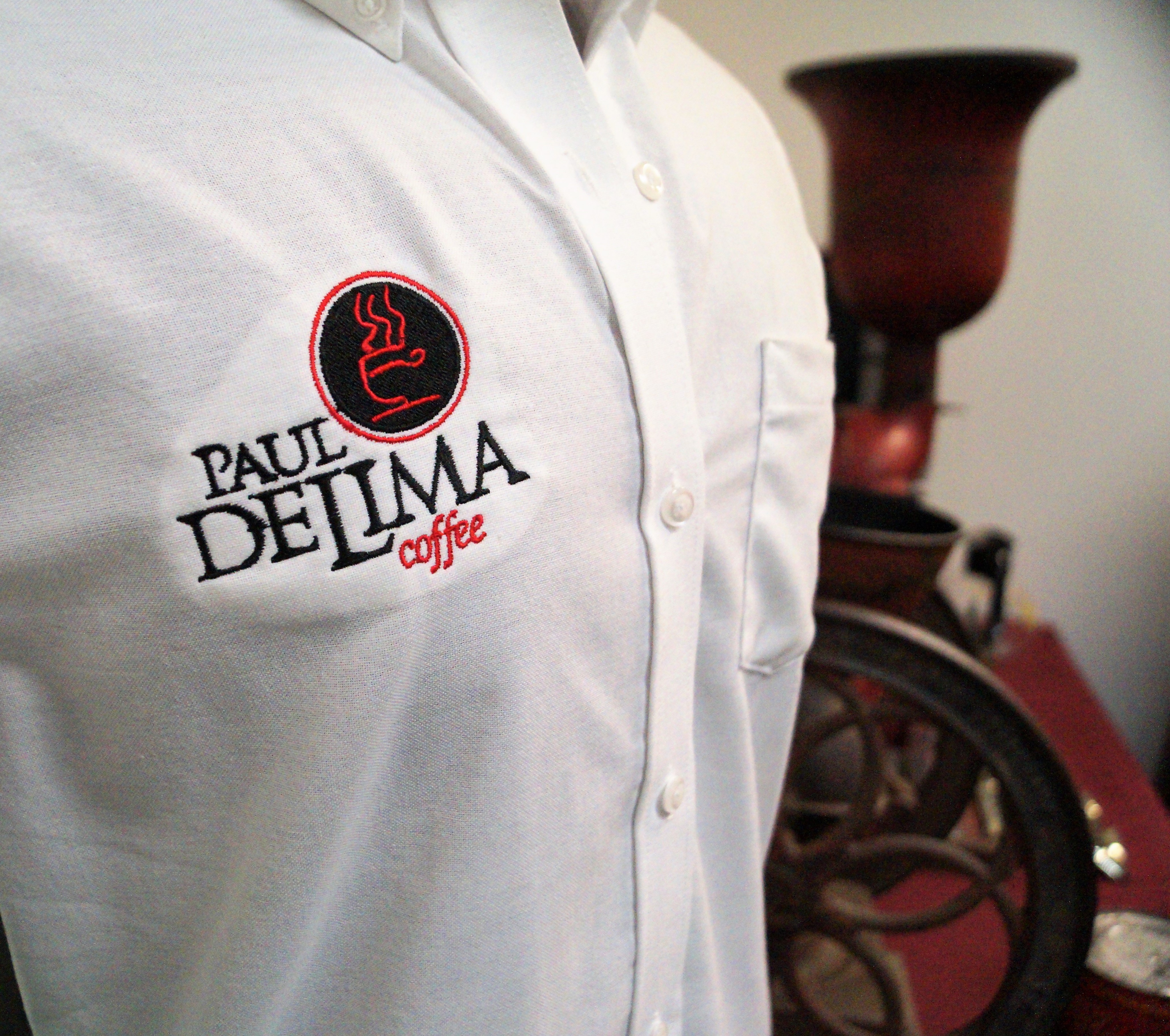 A Paul deLima shirt on display in the museum with old coffee grinding equipment in the background.