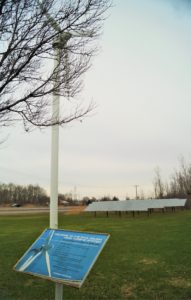 An sign informs visitors of the wind turbine, installed in 2009, that provides renewable energy to the Paul deLima roastery in Cicero, NY.